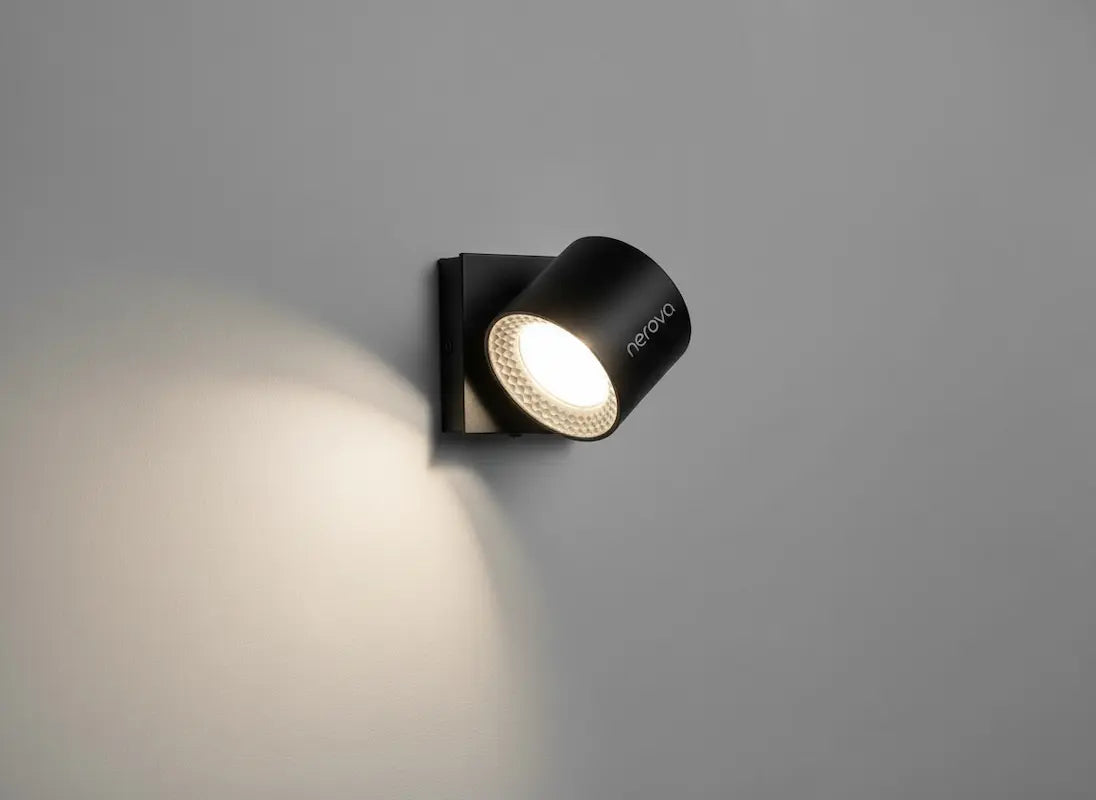 Lampe murale LED Nerova noire orientable avec lumière chaude sur mur gris